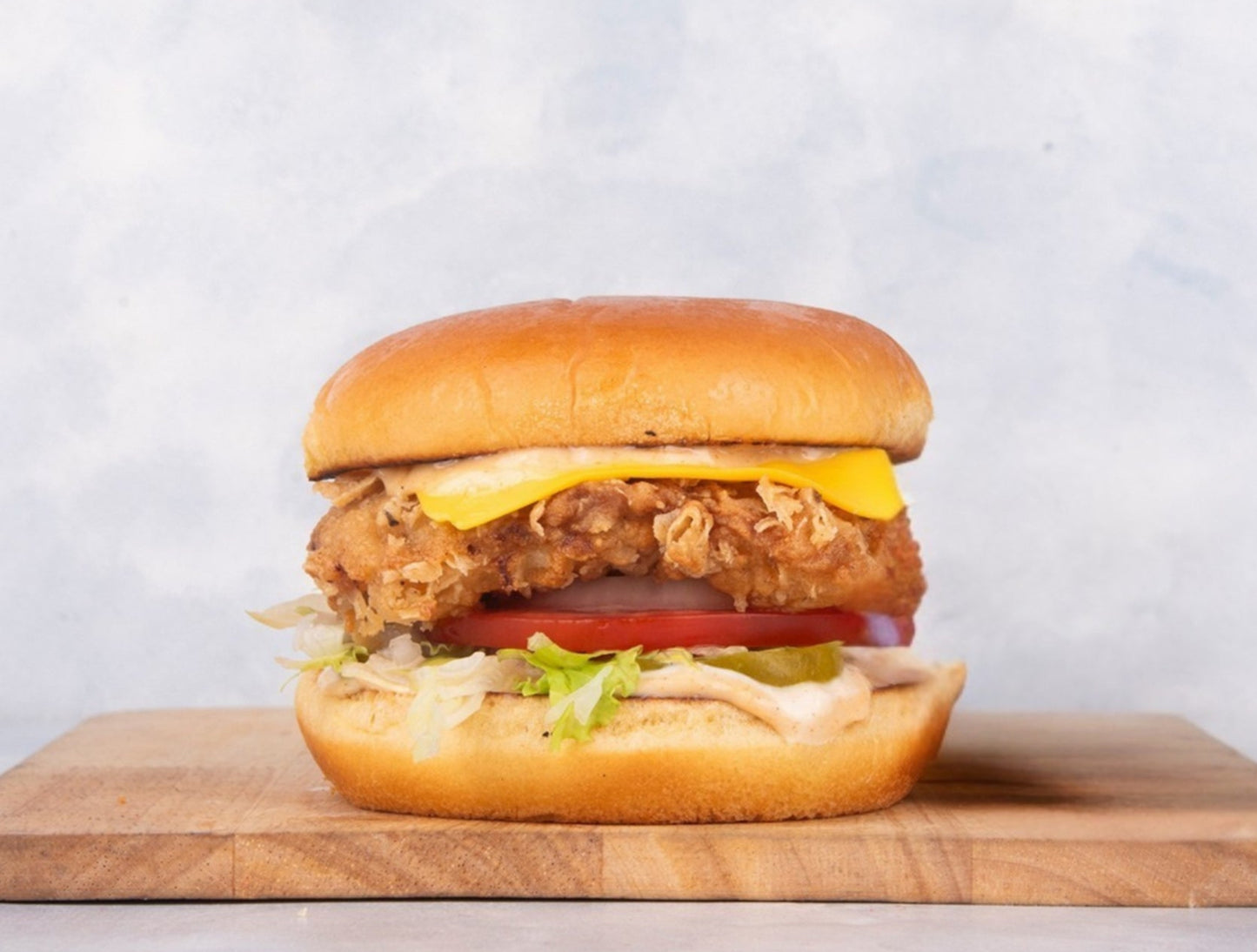 Delicious Grilled Chicken Burger at Heeran Al Dar Cafeteria, featuring a succulent grilled chicken patty, fresh lettuce, juicy tomatoes, creamy cheese, and customizable toppings for a flavorful meal.