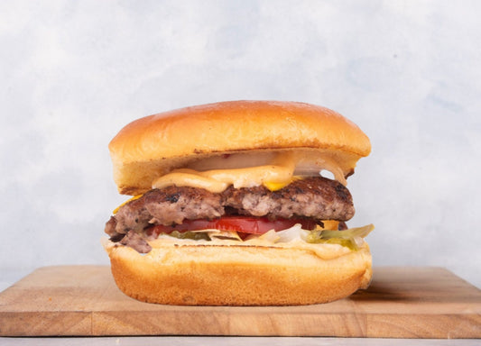 Delicious Heraan Burger served at Heraan Al Dar Cafeteria, featuring fresh, grilled meat marinated in special spices, and served with a unique sauce in a soft bun.